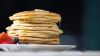 Pancakes on plate with fruit on table