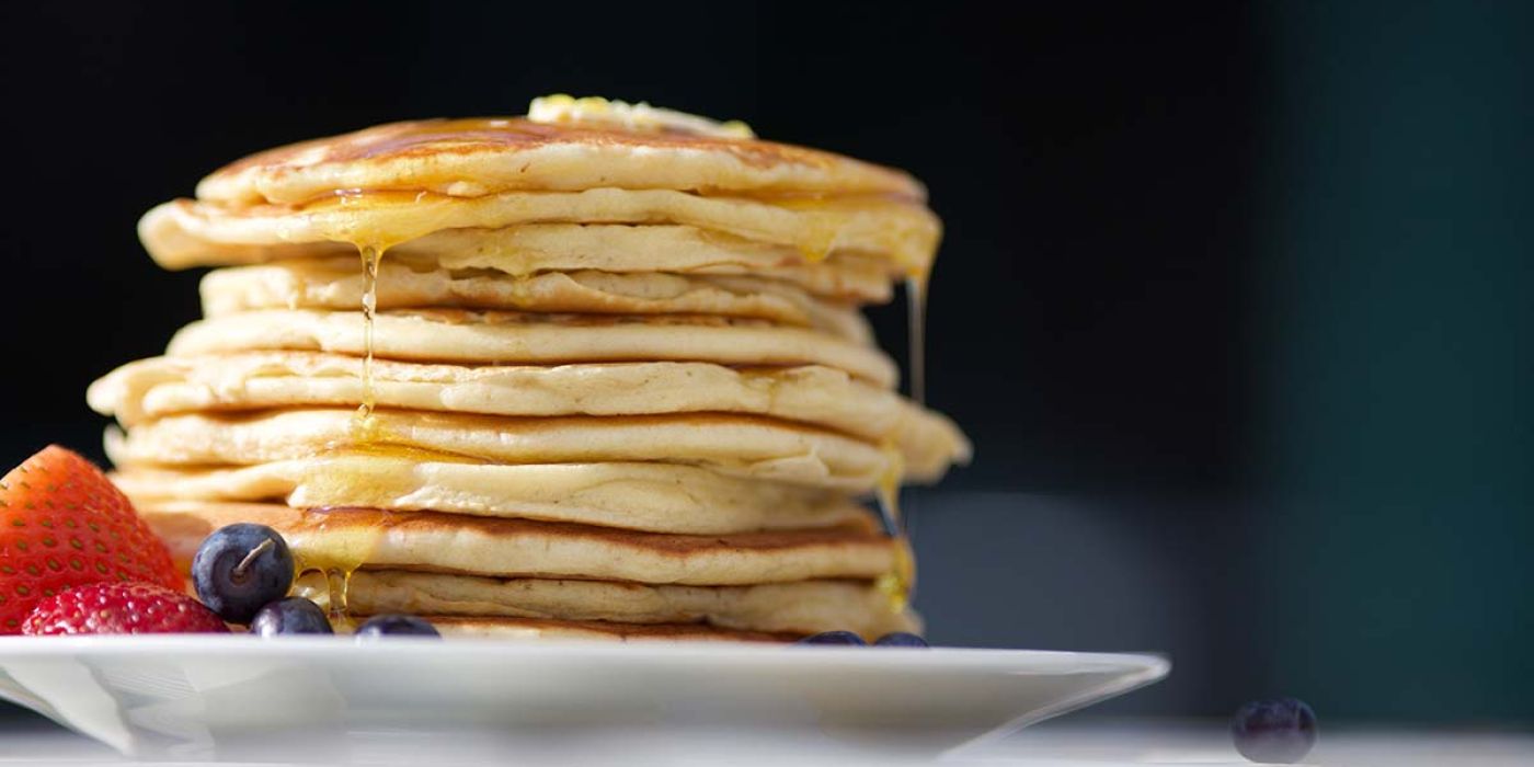 Pancakes on plate with fruit on table