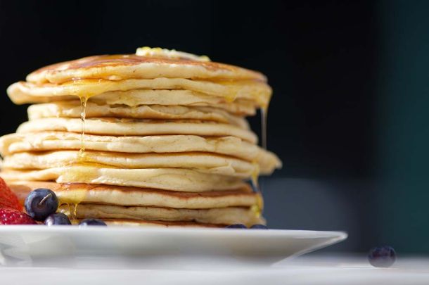 Pancakes on plate with fruit on table