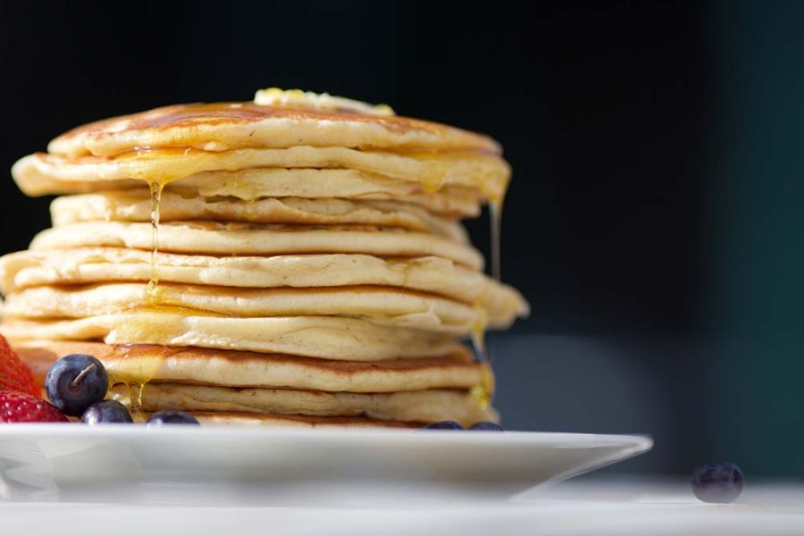 Pancakes on plate with fruit on table